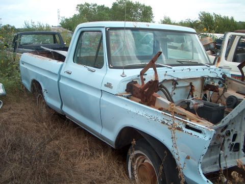 1979 Ford Bronco - Junkyard scene a light blue 1979 Ford F-Series pickup truck with its hood open.