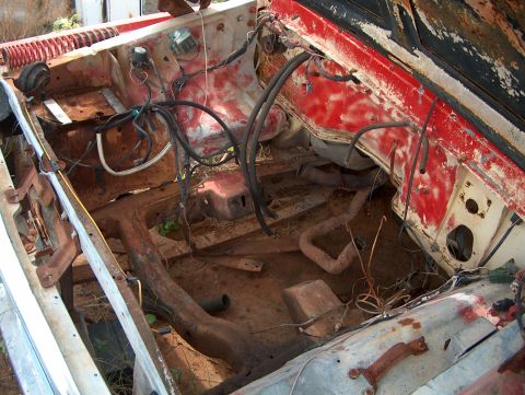 1979 Ford Bronco - The engine bay of a heavily rusted vehicle is visible, with many wires and engine components exposed.