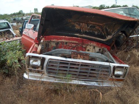 1979 Ford Bronco - This 1979 Ford Bronco sits in a junkyard, its hood propped open, revealing its engine bay.