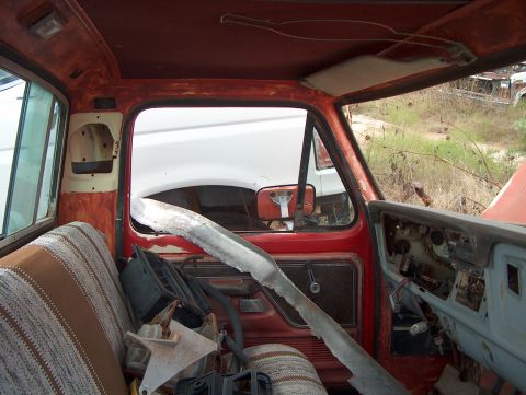 1979 Ford Bronco - The interior of a 1979 Ford Bronco shows signs of wear and tear, with another vehicle visible outside.