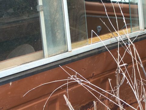1979 Ford Bronco - Close-up of a 1979 Ford Bronco's interior door panel and window frame, showing the window crank.