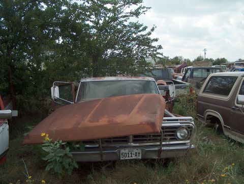 1979 Ford Bronco - Junkyard scene with a rusty 1973 Ford F-Series pickup truck in the foreground.
