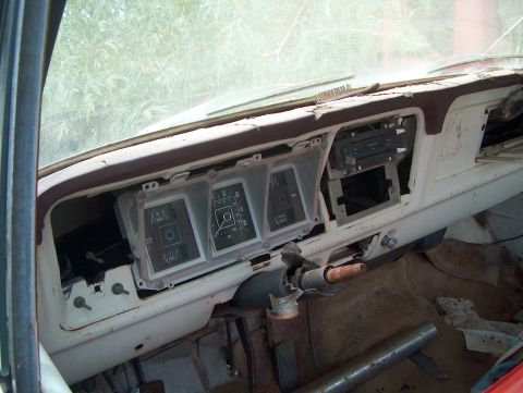 1979 Ford Bronco - The interior of a weathered vehicle shows a damaged dashboard with missing components and a stripped steering column.