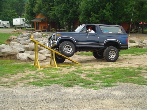 1984 Ford Bronco - Blue Ford Bronco navigating an off-road obstacle course.