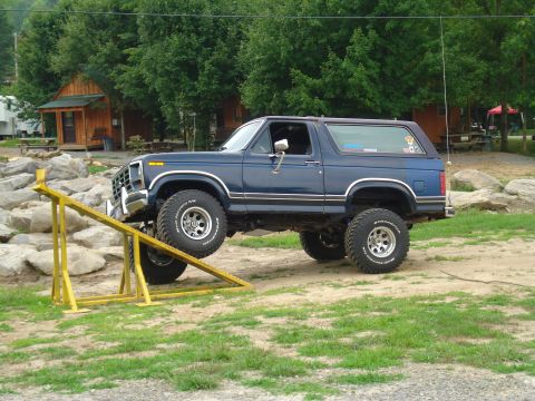 1984 Ford Bronco - This lifted Ford Bronco is navigating an obstacle course with a yellow ramp.