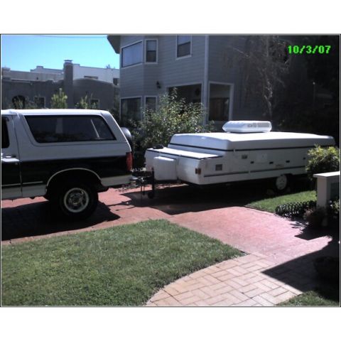 1995 Ford Bronco - A two-tone Ford Bronco is hitched to a pop-up camper in a driveway.