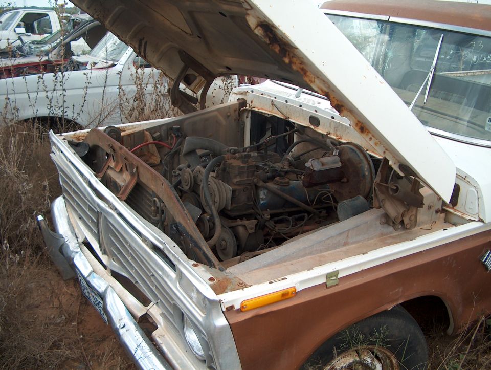 1979 Ford Bronco engine bay with hood open, showing engine and radiator. Another vehicle is visible in the background