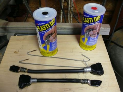 1988 Ford Bronco - Automotive parts and Plasti Dip cans are laid out on a wooden surface, suggesting a repair or modification project.