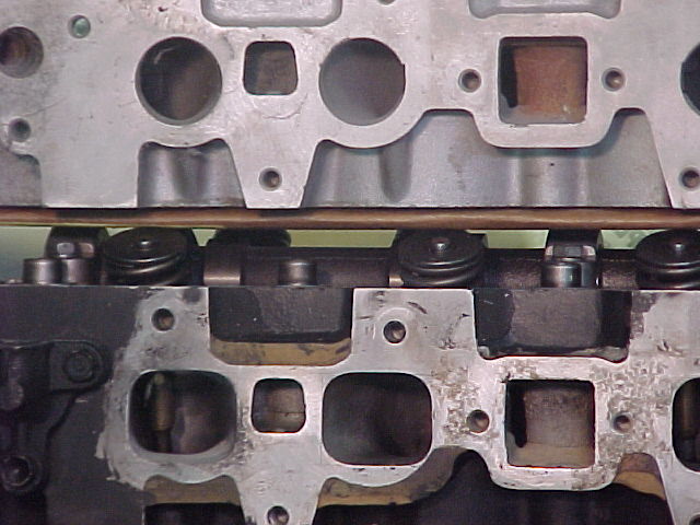 Two bare engine cylinder heads compared side by side, showing ports and valve springs