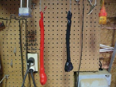 1988 Ford Bronco - Two battery cables, one red and one black, hang from a pegboard in a workshop. Text on the wall indicates 'B 93' and '6203 RS'.