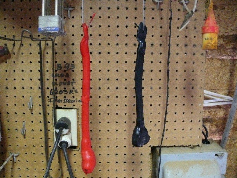 Red and black battery cables hanging on a pegboard wall