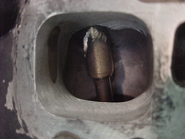 Close-up of a carbide burr tool inside a cylinder head port during porting work