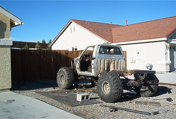 1982 Toyota 4Runner chassis with oversized tires, stripped body, parked in driveway