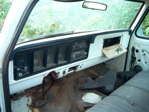 1979 Ford Bronco - The interior of an old truck shows a worn dashboard, cracked windshield, and exposed wiring.