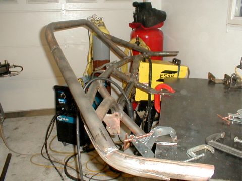 1991 Ford Bronco - Custom roll cage fabrication in progress, showing welded metal tubes and welding equipment.