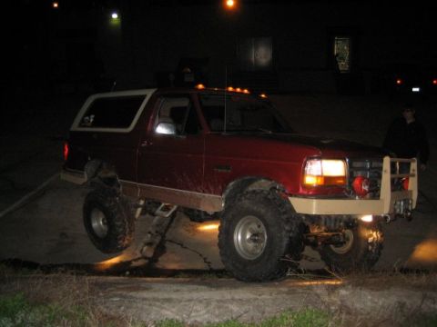 1995 Ford Bronco - This lifted 1995 Ford Bronco is shown off-roading at night with its large tires and custom bumper.