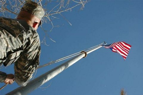 1996 Ford Bronco - Soldier raises the American flag on a flagpole under a clear blue sky.