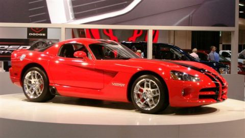 1996 Ford Probe - A red Dodge Viper is displayed at an auto show with other vehicles in the background.