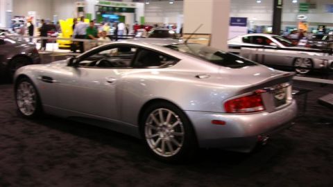1996 Ford Probe - A silver coupe is displayed at an auto show, with other vehicles and people in the background.