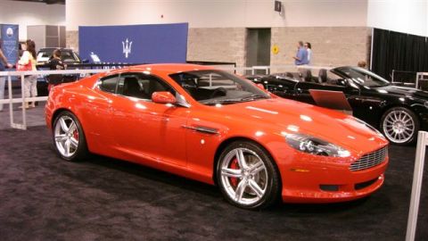 1996 Ford Probe - An orange coupe is displayed at an auto show next to a black convertible.