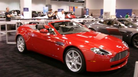 1996 Ford Probe - Red convertible sports car on display at an auto show with other vehicles in the background.