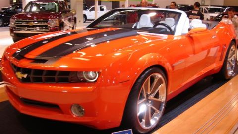 1996 Ford Probe - Orange convertible sports car with black racing stripes on display at an auto show.