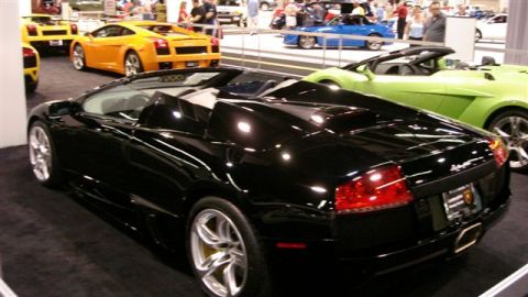 1996 Ford Probe - Several sports cars are displayed at an auto show, including a black convertible in the foreground.