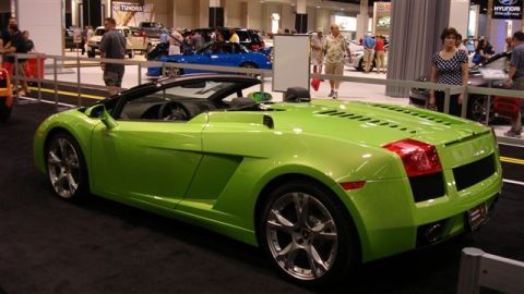 1996 Ford Probe - A bright green convertible sports car is displayed indoors, with other vehicles and people visible in the background.
