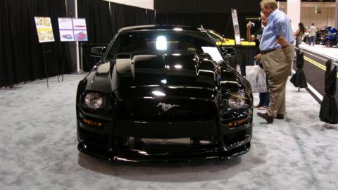 1996 Ford Probe - A black Ford Mustang is displayed at an auto show, a custom hood scoop and a horse emblem.