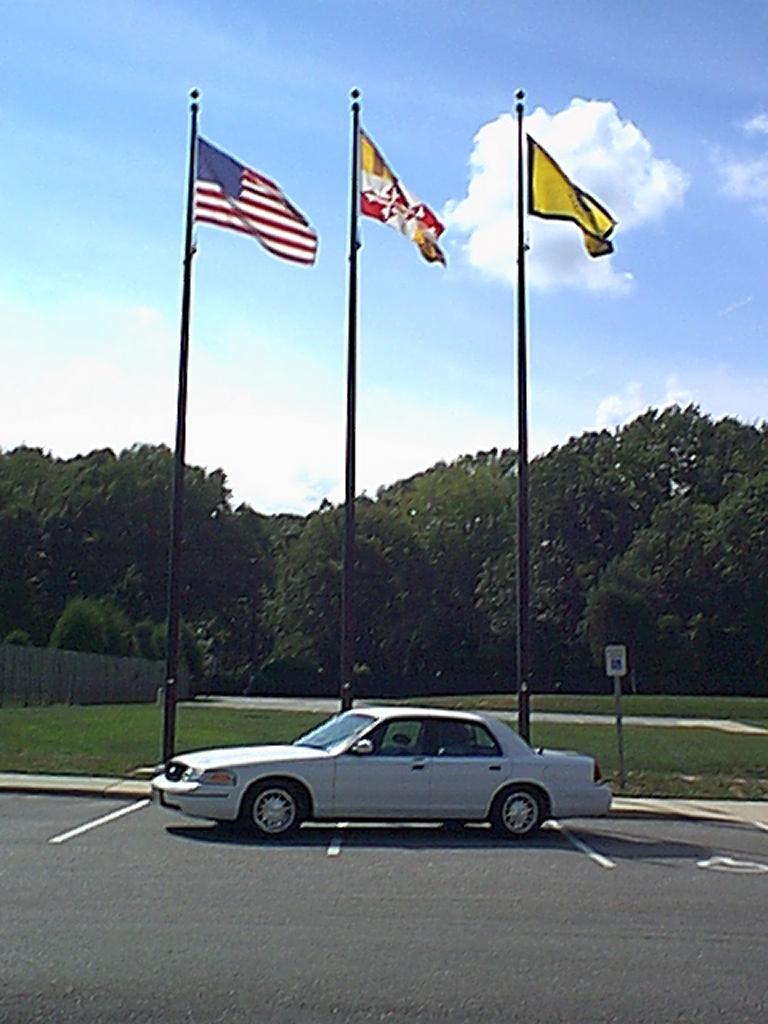 White 1998 Ford Crown Victoria parked next to flagpoles