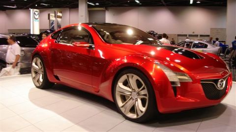 1996 Ford Probe - A red concept car is showcased at an auto show with other vehicles in the background.