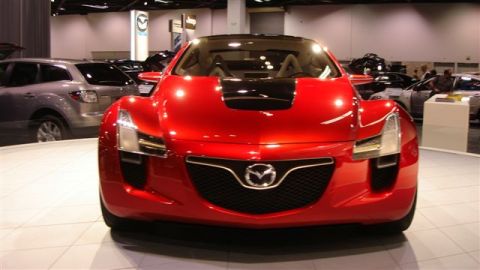 1996 Ford Probe - A red concept car with a prominent Mazda emblem is displayed at an auto show.