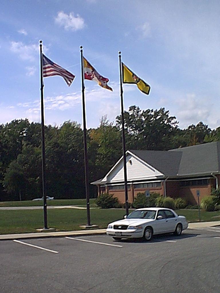 1998 Ford Crown Victoria parked in front of a building with three flags