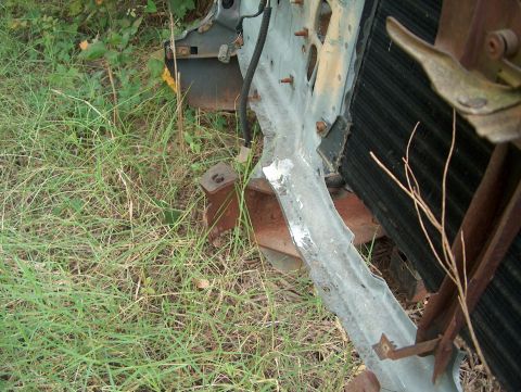 1979 Ford Bronco - Close-up of a damaged 1979 Ford Bronco radiator and front-end structure amidst tall grass.