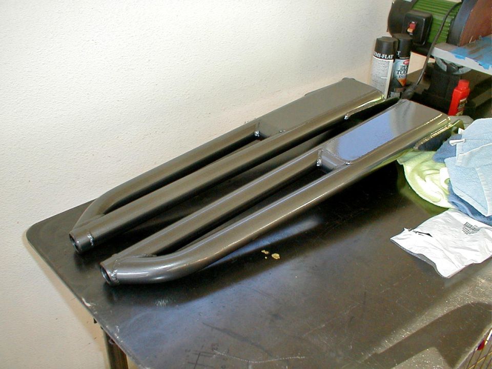 pair of dark gray metal running boards on a workbench