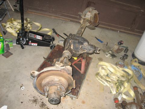 1988 Ford Bronco - A disassembled front axle assembly is shown, with various tools and straps scattered around it.