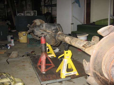 1988 Ford Bronco - A vehicle's rear axle assembly is supported by jack stands in a workshop setting.