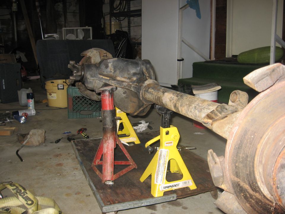 Vehicle rear axle assembly on jack stands in a garage