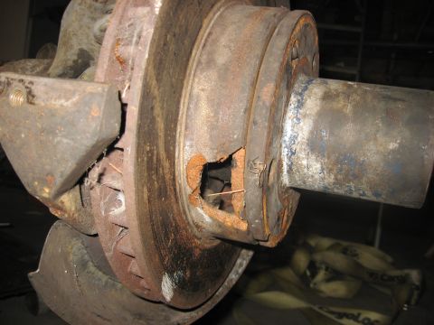 1988 Ford Bronco - Close-up of a heavily corroded vehicle axle and brake rotor assembly.