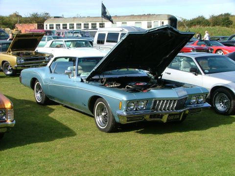 1988 Ford Sport - A light blue 1971 Buick Riviera coupe is displayed with its hood open at an outdoor car show.