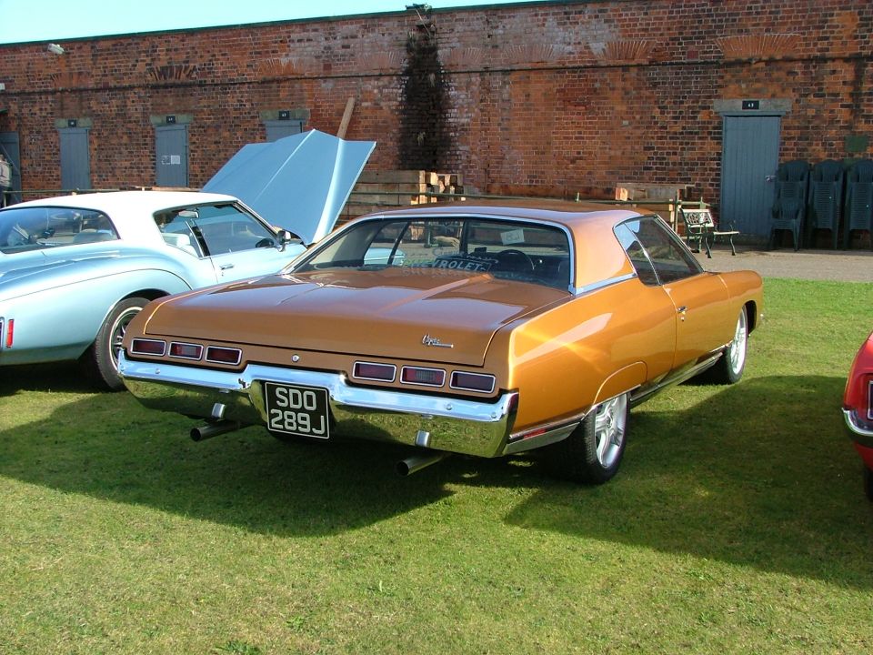 1971 Chevrolet Caprice coupe, rear view, parked on grass. Another car is visible to the left