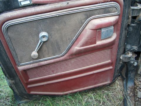 1979 Ford Bronco - The interior door panel of a 1979 Ford Bronco shows its red trim and a functional window crank.