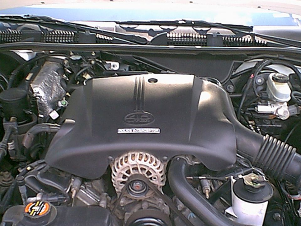 1998 Ford Crown Victoria engine bay, showing the engine cover, alternator, and various hoses and components