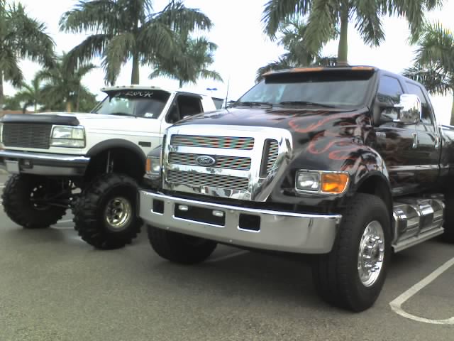 Two lifted Ford trucks, one black with flames, one white