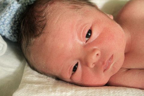 1988 Ford Bronco - A close-up view of a newborn baby's face resting on a white surface.