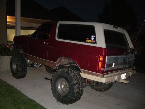 1995 Ford Bronco - This lifted 1995 Ford Bronco features oversized tires and a two-tone paint scheme, seen from the rear.