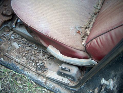 1979 Ford Bronco - The interior of this 1979 Ford Bronco shows significant wear and tear, with debris scattered across the floor and seat.