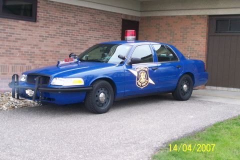 2003 Ford Crown Victoria - Michigan State Police Crown Victoria, likely a 2003 model, parked outside a building.