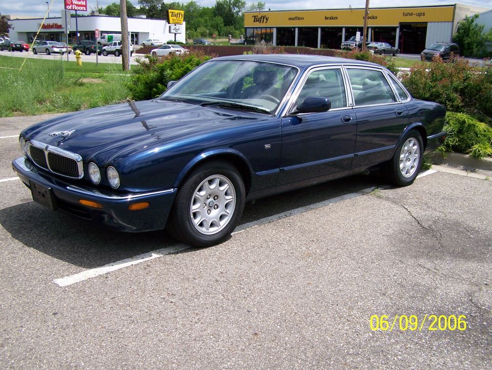 Dark blue Jaguar sedan parked in a lot, front 3/4 view