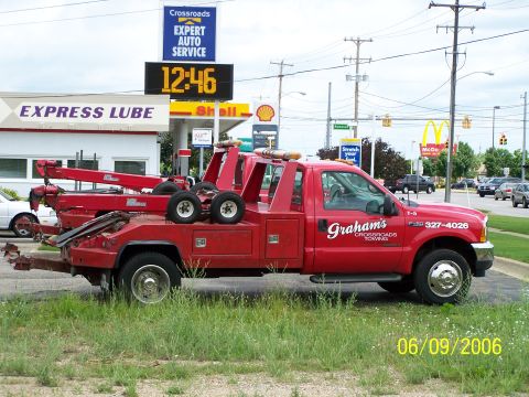 2003 Ford Crown Victoria - A red tow truck is parked near a gas station and fast food restaurant.